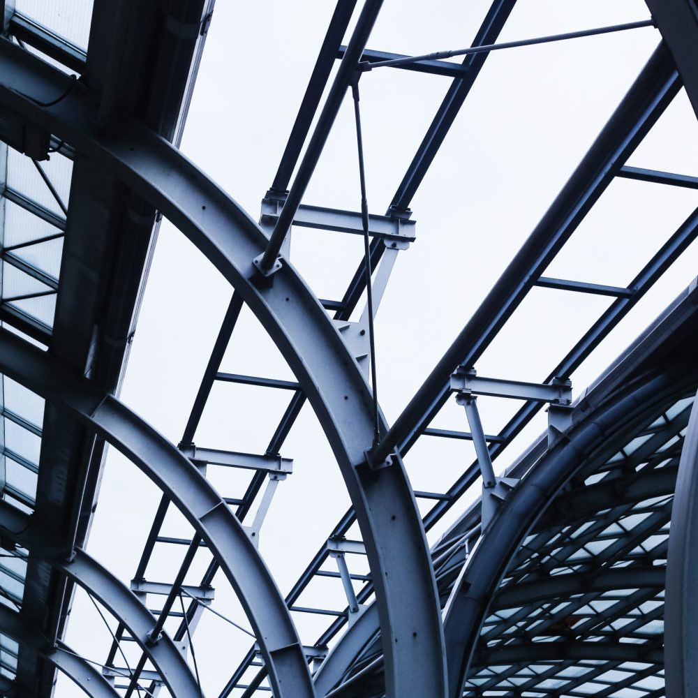 Modern steel and glass architecture. Industrial construction detail with metal beams and transparent roof. Urban structural engineering with geometric framework. Contemporary city infrastructure.