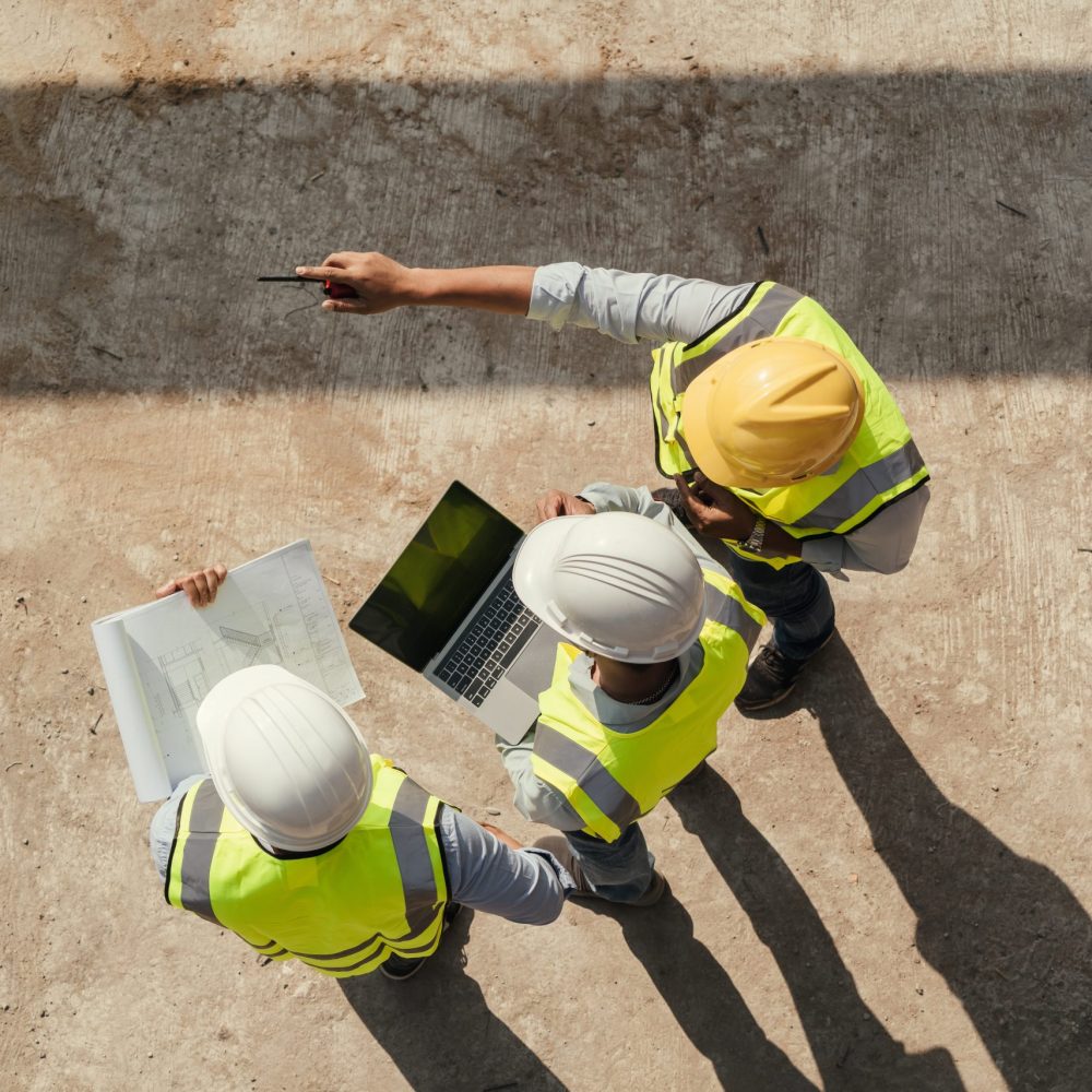 Top view, Team engineer building inspection use tablet computer and blueprint working at construction site. Civil Engineer, Contractor and Architect discussing in construction site.
